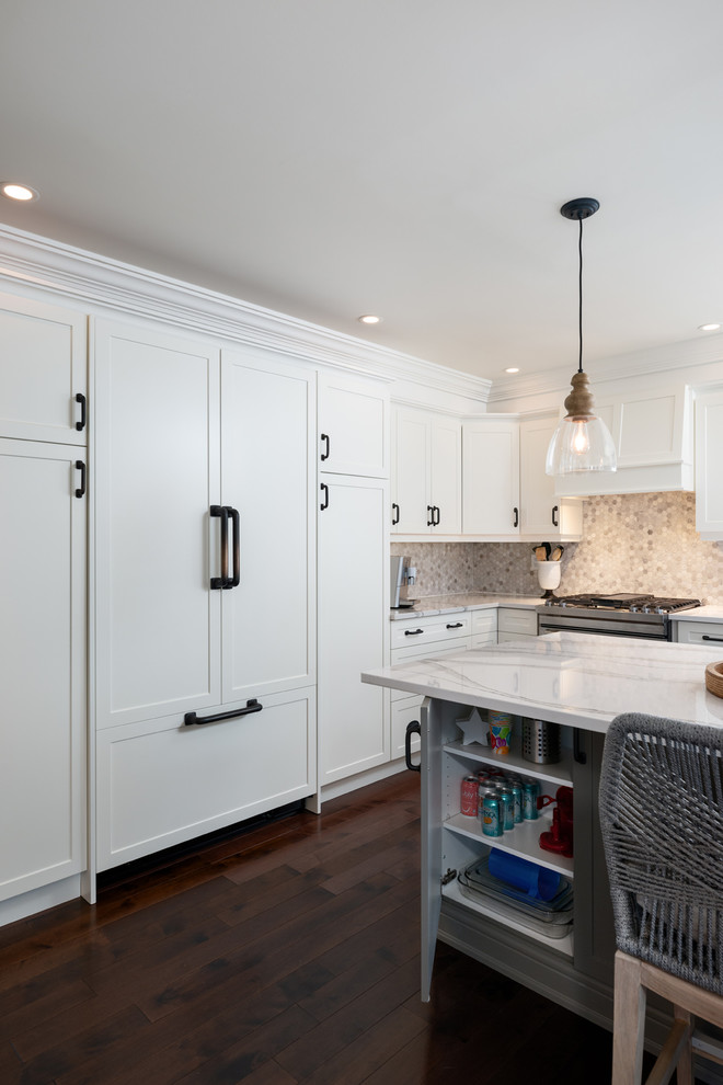 Example of a transitional dark wood floor and brown floor kitchen design with white cabinets, quartz countertops, paneled appliances, an island and white countertops
