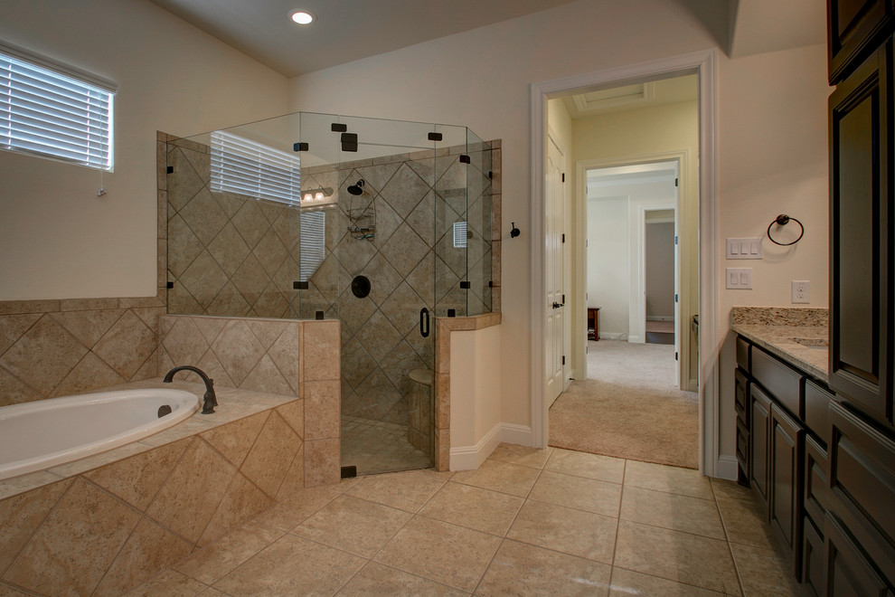 Photo of a country bathroom in Austin with raised-panel cabinets, brown cabinets, a drop-in tub, a corner shower, beige tile, porcelain tile, white walls, porcelain floors, an undermount sink, granite benchtops, beige floor, a hinged shower door and beige benchtops.