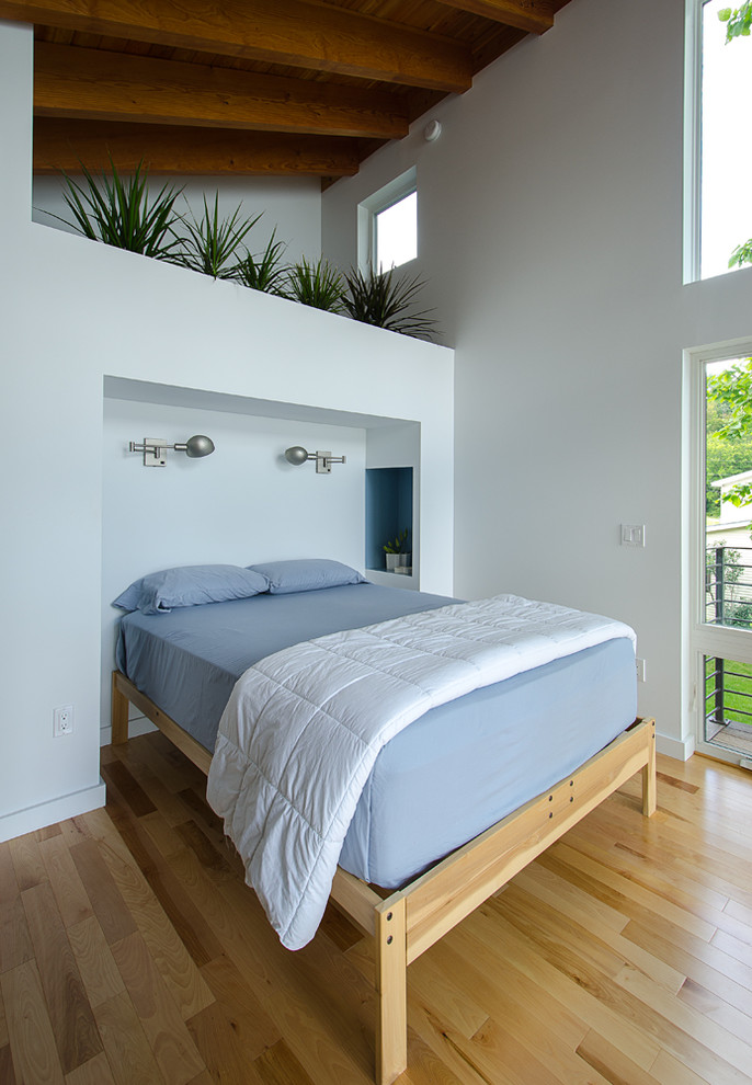 Photo of a mid-sized contemporary master bedroom in Burlington with white walls, medium hardwood floors and yellow floor.
