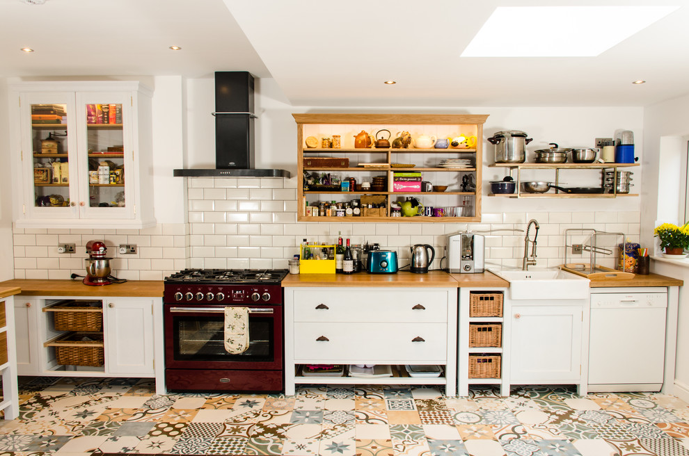 Design ideas for a country l-shaped kitchen in Other with a farmhouse sink, shaker cabinets, white cabinets, wood benchtops, beige splashback, subway tile splashback, coloured appliances, no island and multi-coloured floor.