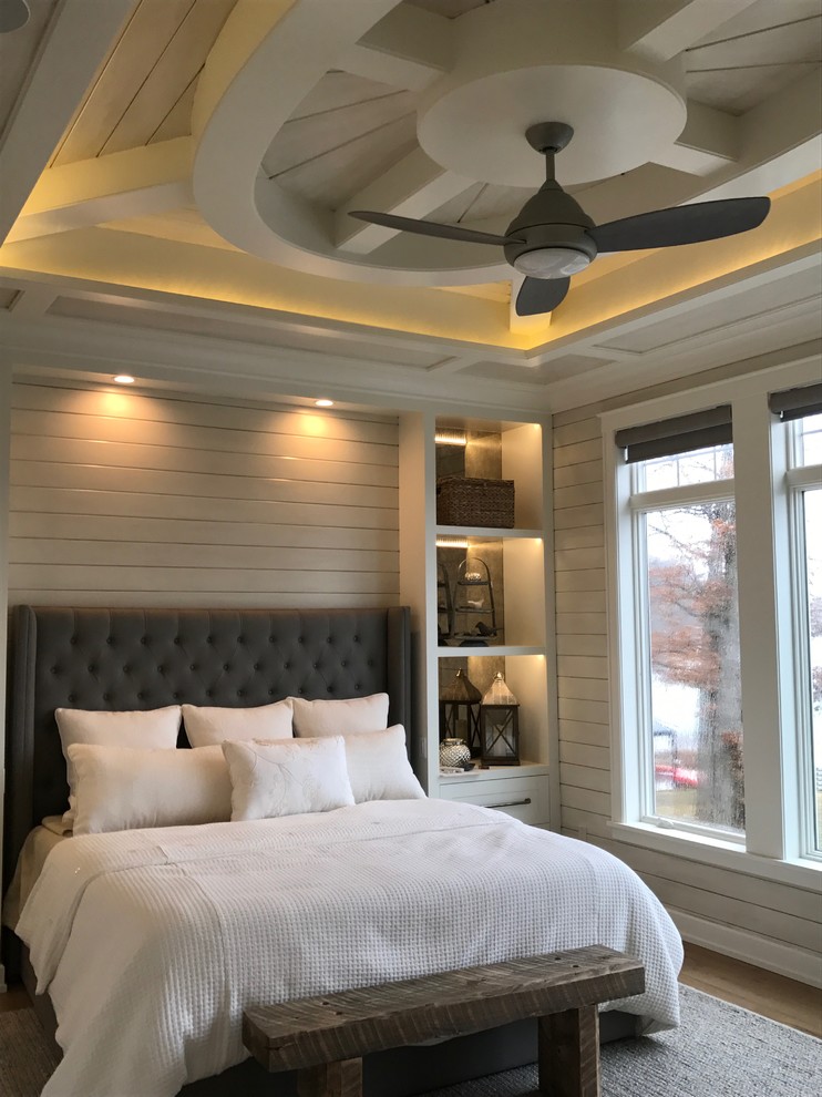 This is an example of a large beach style master bedroom in Detroit with grey walls, medium hardwood floors, no fireplace and brown floor.