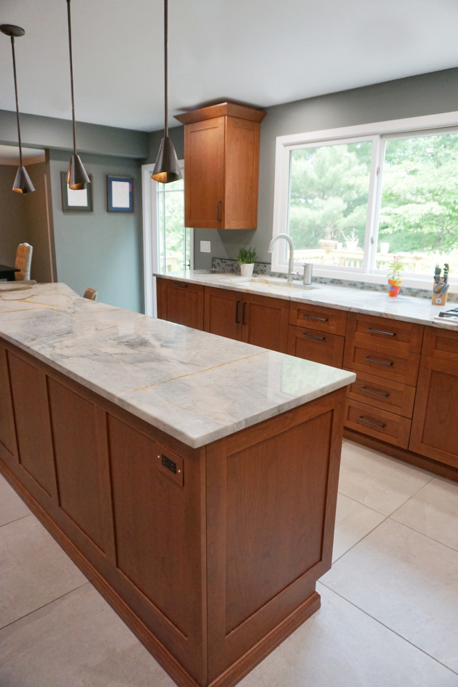 Example of a mid-sized transitional porcelain tile and gray floor eat-in kitchen design with recessed-panel cabinets, medium tone wood cabinets, quartzite countertops, green backsplash, mosaic tile backsplash, stainless steel appliances and an island