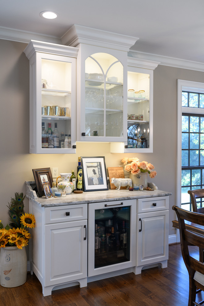 Kitchen - large transitional l-shaped dark wood floor and brown floor kitchen idea with an undermount sink, raised-panel cabinets, white cabinets, quartzite countertops, white backsplash, marble backsplash, stainless steel appliances and an island