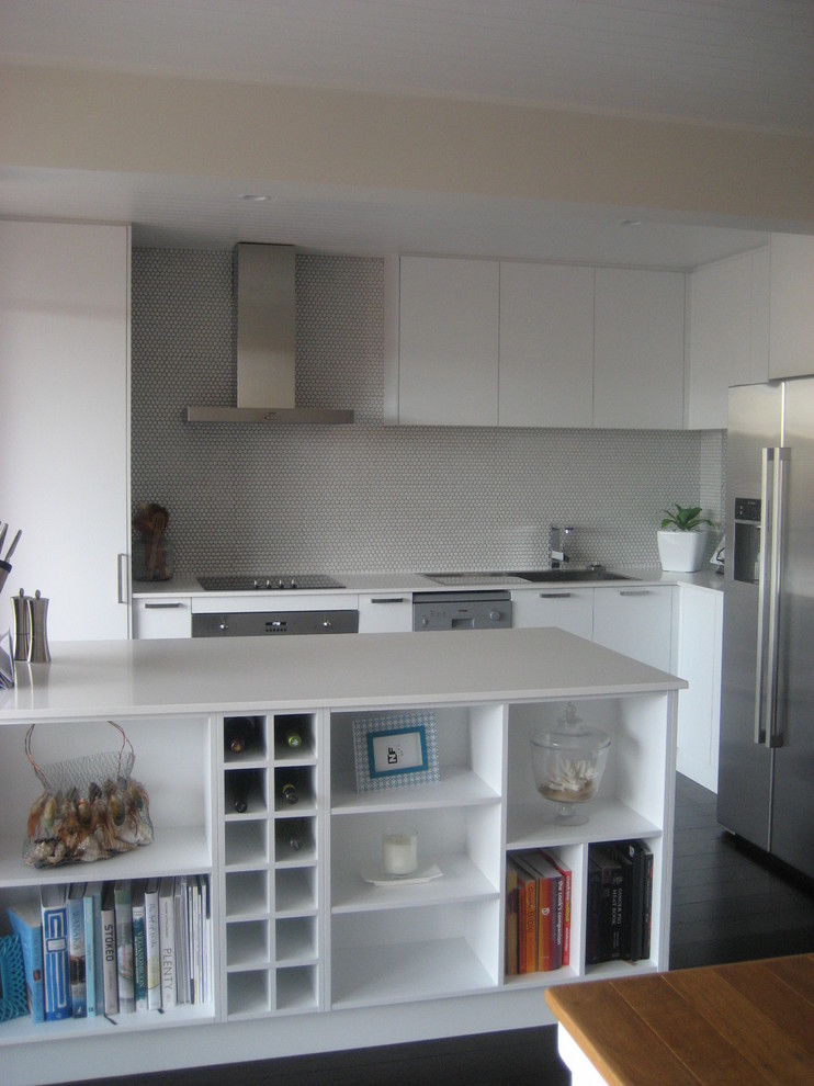 This is an example of a small modern l-shaped kitchen in Sydney with a single-bowl sink, flat-panel cabinets, white cabinets, quartz benchtops, white splashback, stainless steel appliances and with island.