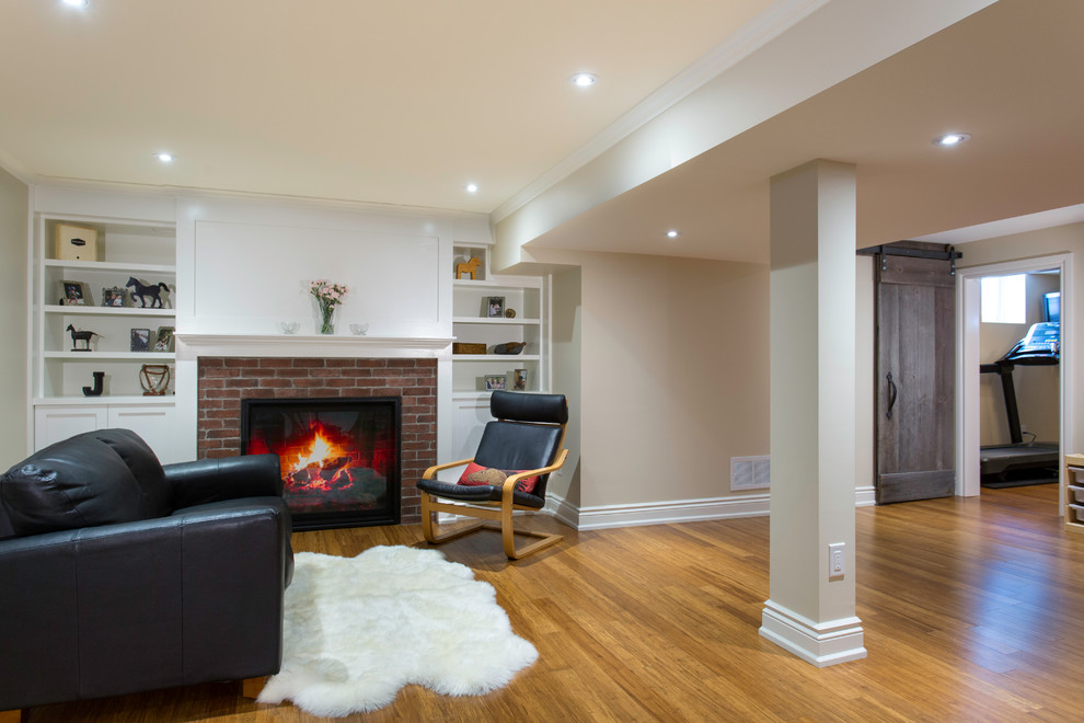 Fully buried basement in Toronto with bamboo floors, a standard fireplace and a brick fireplace surround.