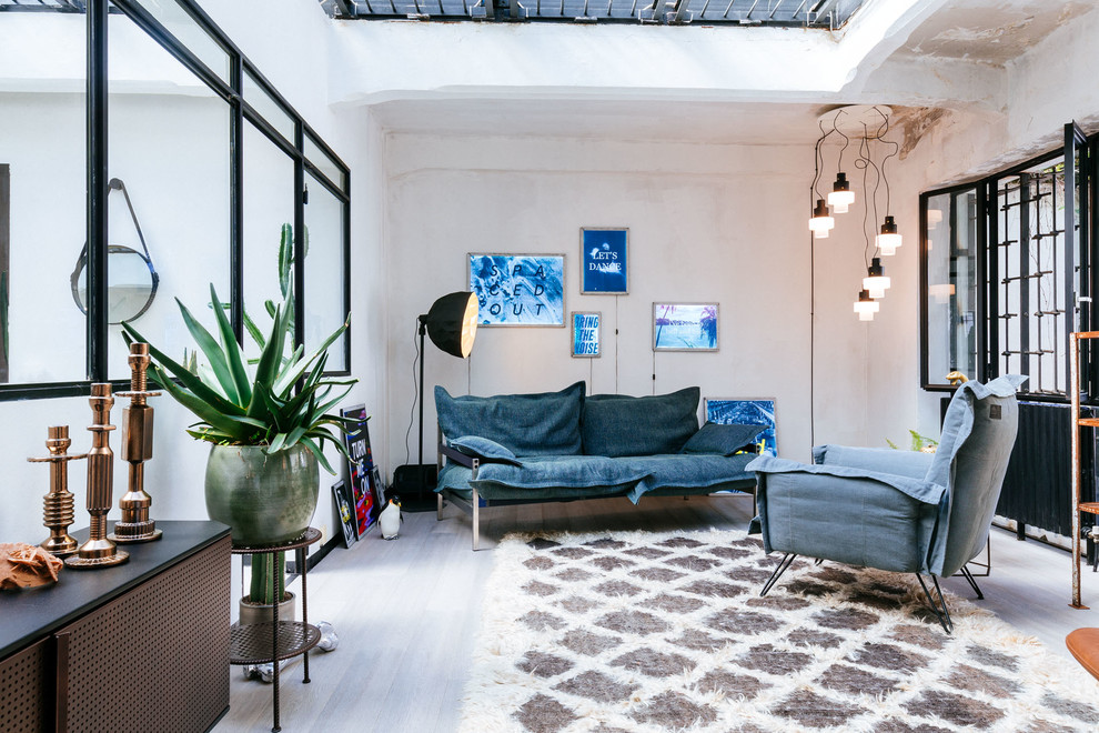 Photo of a mid-sized industrial enclosed living room in Milan with white walls, no tv and grey floor.