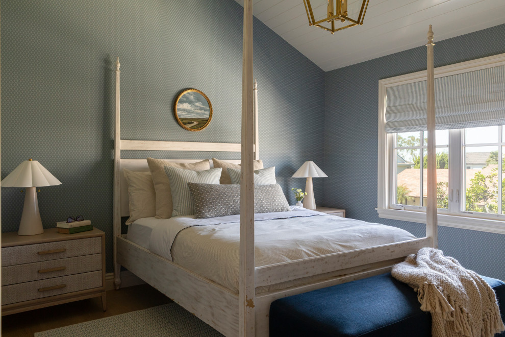 Example of a beach style medium tone wood floor, vaulted ceiling and wallpaper bedroom design in Orange County with blue walls