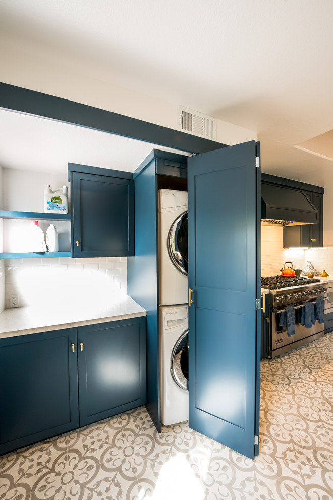 Inspiration for a small contemporary single-wall dedicated laundry room in Los Angeles with shaker cabinets, blue cabinets, quartzite benchtops, white walls, ceramic floors, a stacked washer and dryer and white floor.
