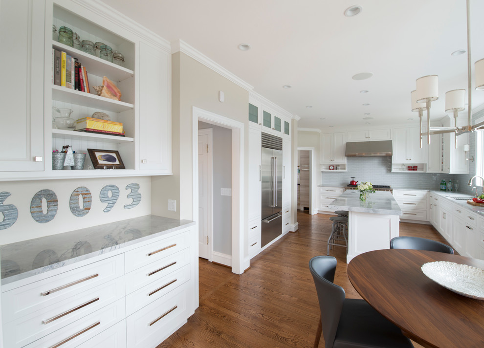 Inspiration for a mid-sized transitional l-shaped dark wood floor eat-in kitchen remodel in Chicago with an undermount sink, white cabinets, quartzite countertops, white backsplash, glass tile backsplash, stainless steel appliances, an island and recessed-panel cabinets