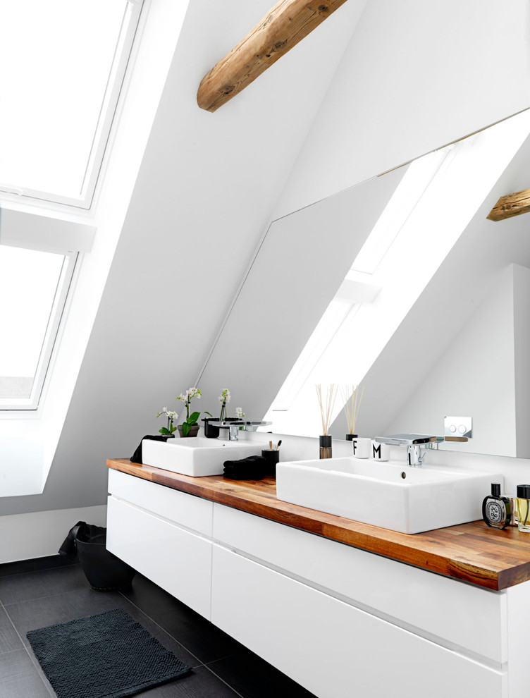 Mid-sized scandinavian master bathroom in Odense with flat-panel cabinets, white cabinets, white tile, stone tile, white walls, ceramic floors, a trough sink and wood benchtops.