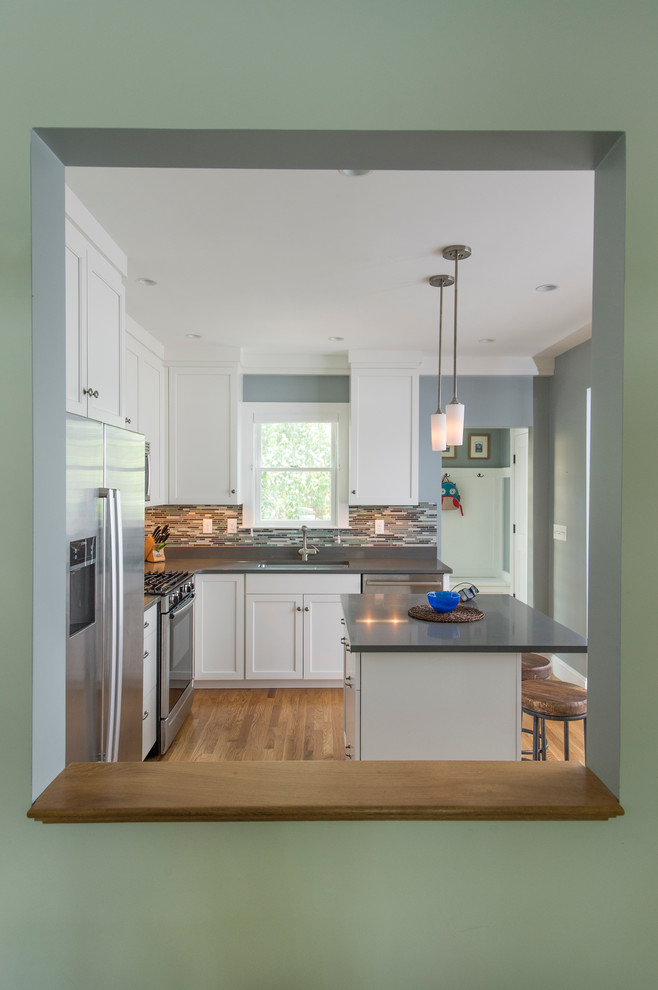 Inspiration for a mid-sized transitional l-shaped medium tone wood floor eat-in kitchen remodel in Boston with shaker cabinets, white cabinets, quartz countertops, gray backsplash, glass sheet backsplash, stainless steel appliances, an island and a single-bowl sink