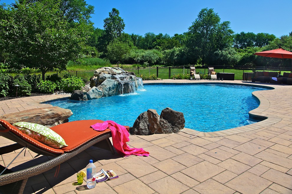 Inspiration for a mid-sized country backyard custom-shaped pool in New York with a water feature and brick pavers.