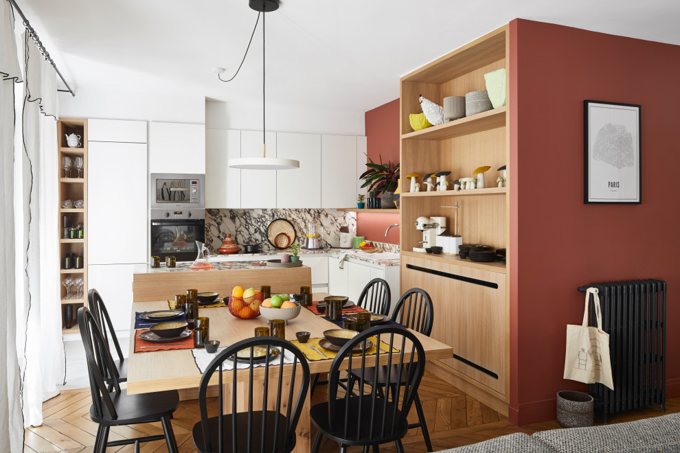 Idées déco pour une cuisine américaine encastrable contemporaine en L de taille moyenne avec un évier posé, un placard à porte plane, des portes de placard blanches, une crédence grise, îlot, un sol marron et un plan de travail gris.