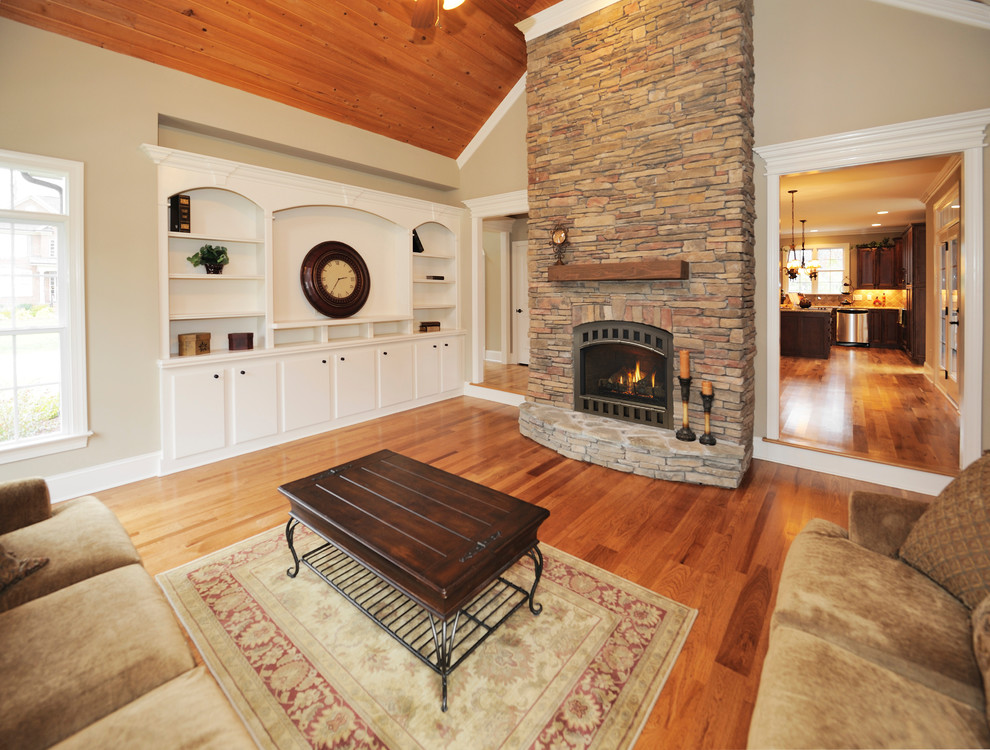 Large transitional enclosed living room in Portland Maine with beige walls, medium hardwood floors, a standard fireplace, a stone fireplace surround, no tv and brown floor.