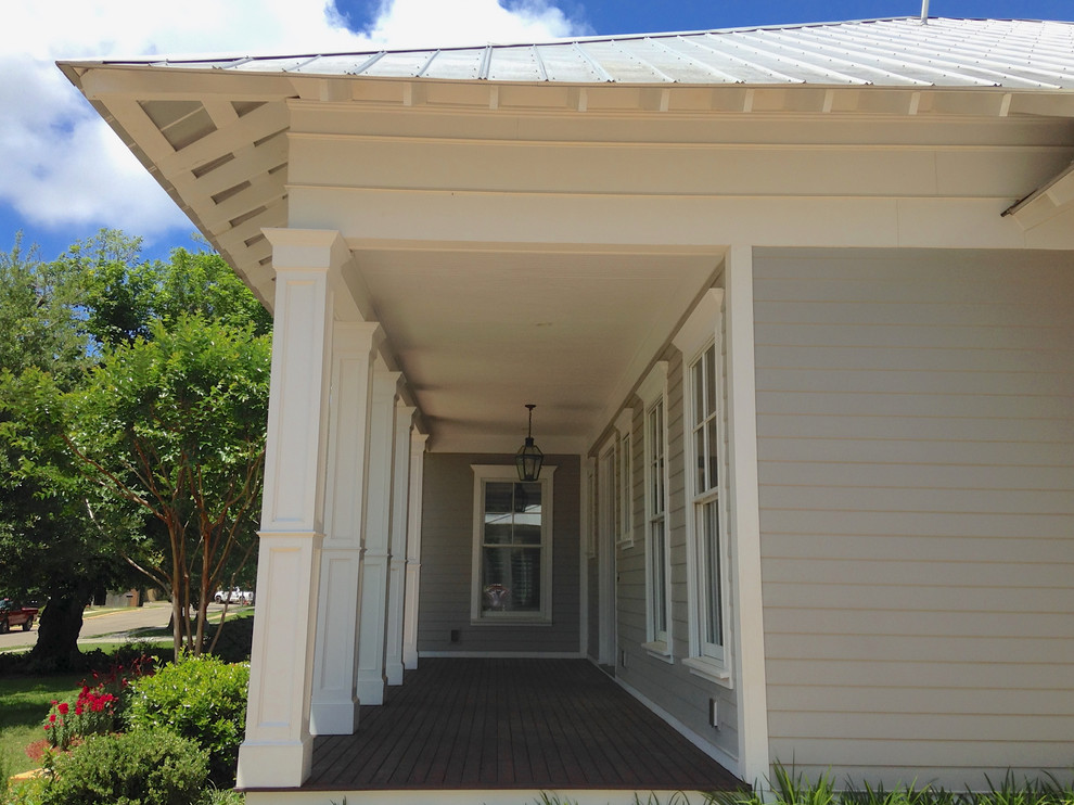 Photo of a large traditional front yard verandah in New Orleans with a roof extension.