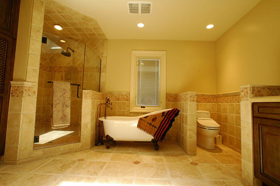 Design ideas for a mid-sized traditional master bathroom in San Francisco with recessed-panel cabinets, dark wood cabinets, a freestanding tub, a corner shower, a one-piece toilet, beige tile, stone tile, beige walls and travertine floors.