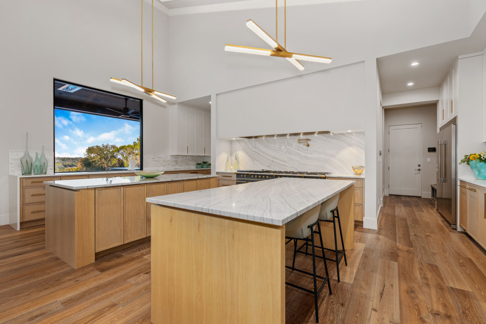 Kitchen - large kitchen idea with light wood cabinets, white backsplash, stainless steel appliances, two islands and white countertops