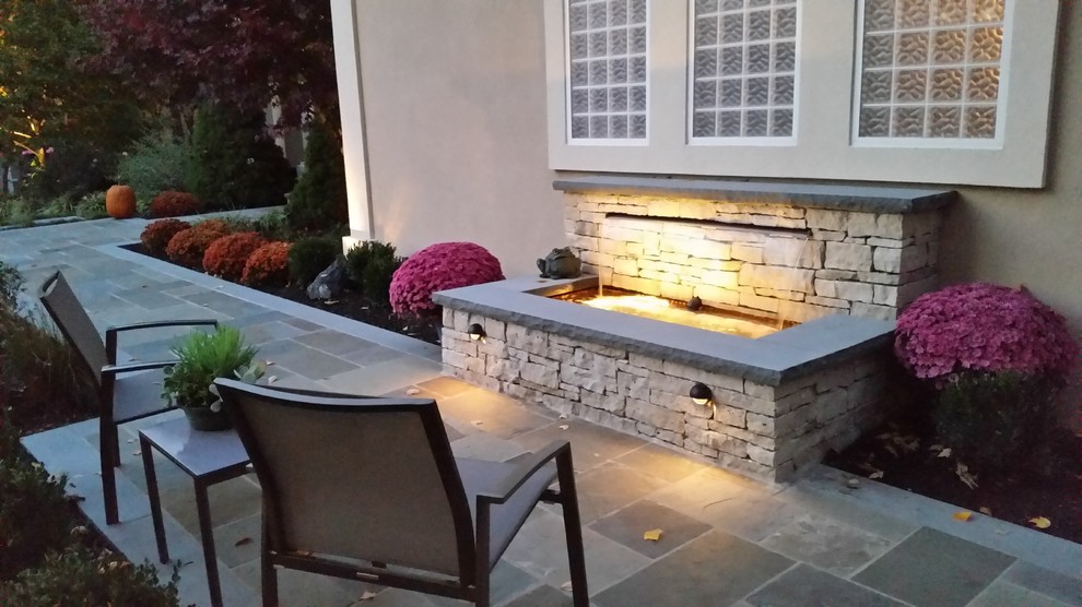 Small contemporary front yard patio in Kansas City with a water feature and natural stone pavers.