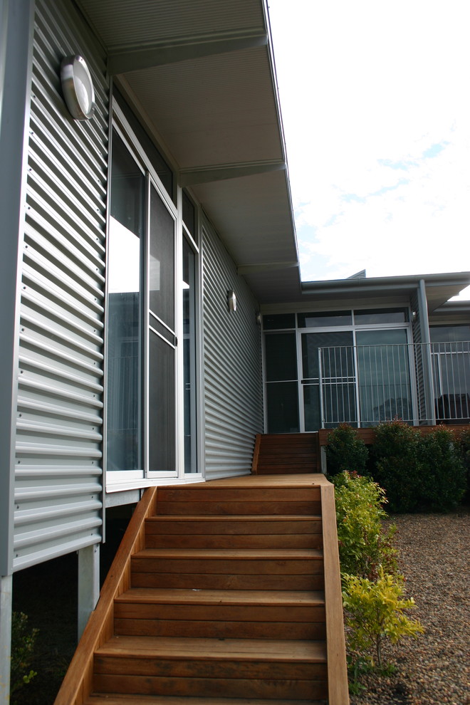 Photo of a mid-sized industrial split-level grey house exterior in Sydney with metal siding.