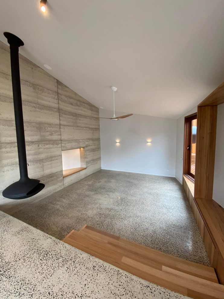 Idée de décoration pour un salon urbain de taille moyenne et ouvert avec un mur gris, sol en béton ciré, cheminée suspendue et un sol gris.