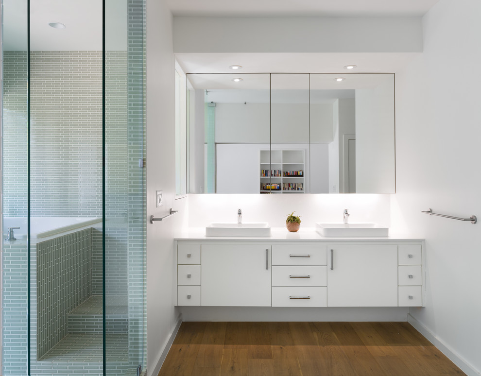 Inspiration for a mid-sized scandinavian master bathroom in Austin with a vessel sink, flat-panel cabinets, white cabinets, engineered quartz benchtops, a japanese tub, a curbless shower, green tile, glass tile, white walls, medium hardwood floors and brown floor.