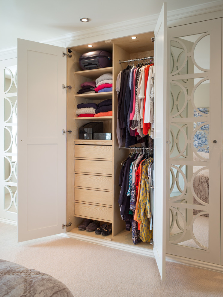 Photo of a transitional gender-neutral storage and wardrobe in Other with glass-front cabinets, white cabinets, carpet and beige floor.