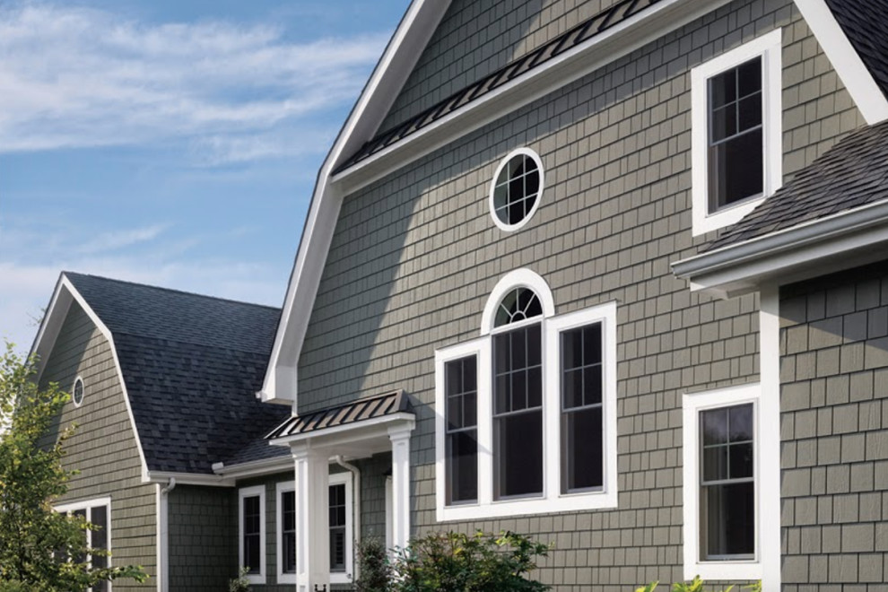 Photo of a large country two-storey grey house exterior in Boston with vinyl siding, a gambrel roof and a shingle roof.