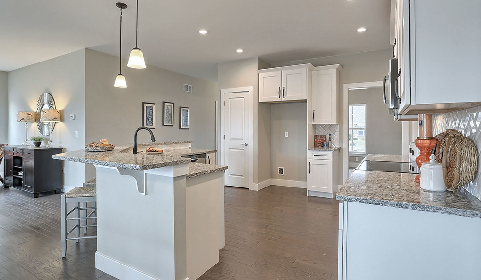 Photo of a mid-sized traditional l-shaped eat-in kitchen in Other with a double-bowl sink, white cabinets, granite benchtops, white splashback, subway tile splashback, stainless steel appliances, with island and medium hardwood floors.