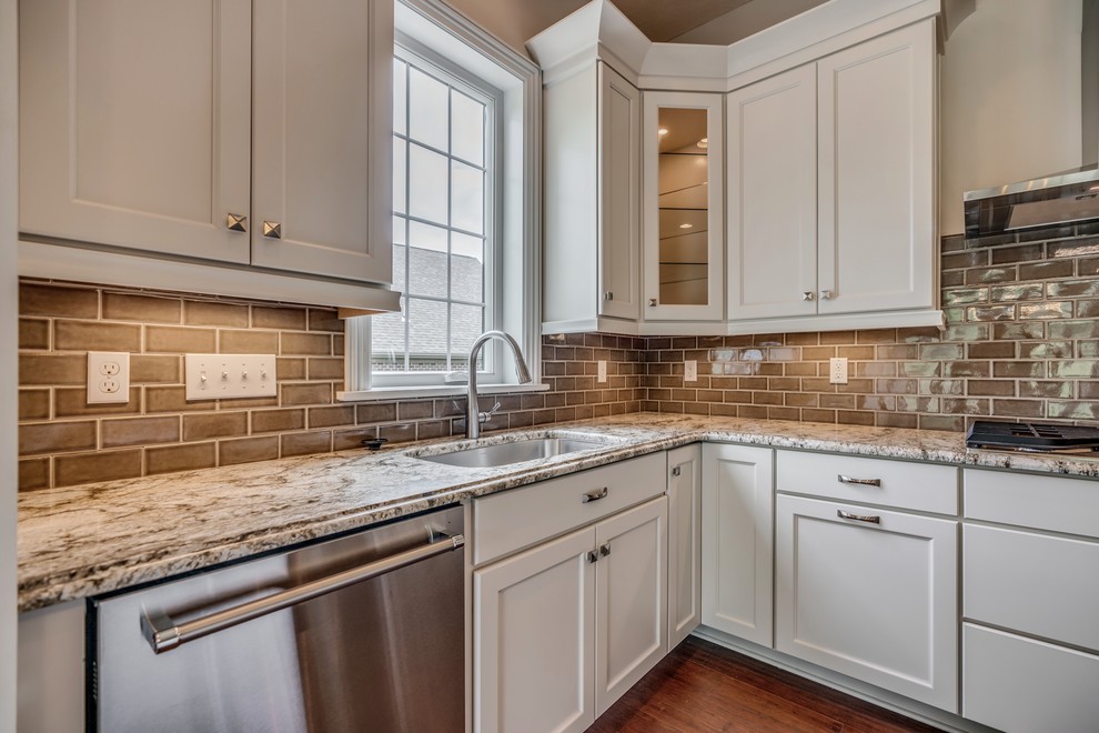 Inspiration for a transitional l-shaped bamboo floor and brown floor eat-in kitchen remodel with an undermount sink, flat-panel cabinets, white cabinets, granite countertops, brown backsplash, subway tile backsplash, stainless steel appliances, an island and brown countertops