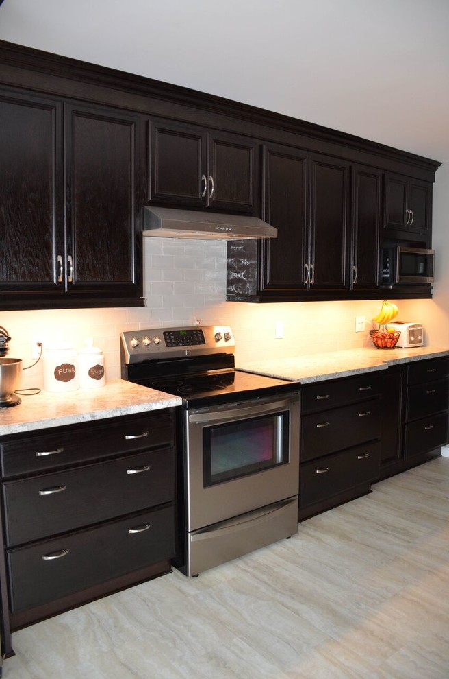Enclosed kitchen - small transitional galley vinyl floor and gray floor enclosed kitchen idea with a drop-in sink, recessed-panel cabinets, dark wood cabinets, laminate countertops, glass tile backsplash, stainless steel appliances and no island