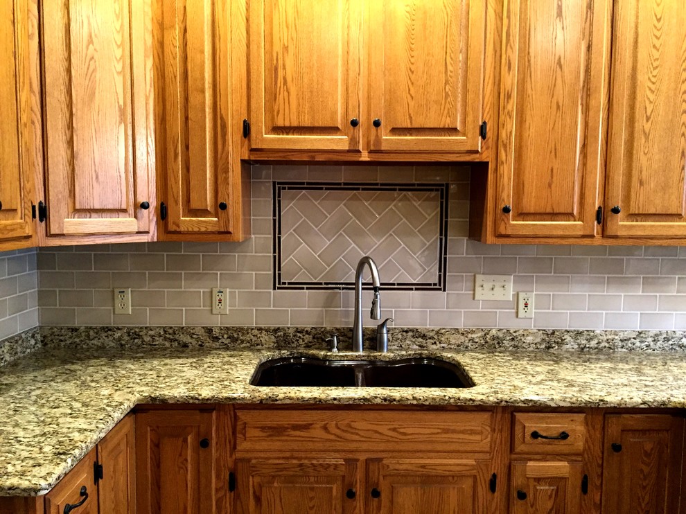 Example of an eat-in kitchen design in Milwaukee with a double-bowl sink, raised-panel cabinets, medium tone wood cabinets, gray backsplash, subway tile backsplash and stainless steel appliances