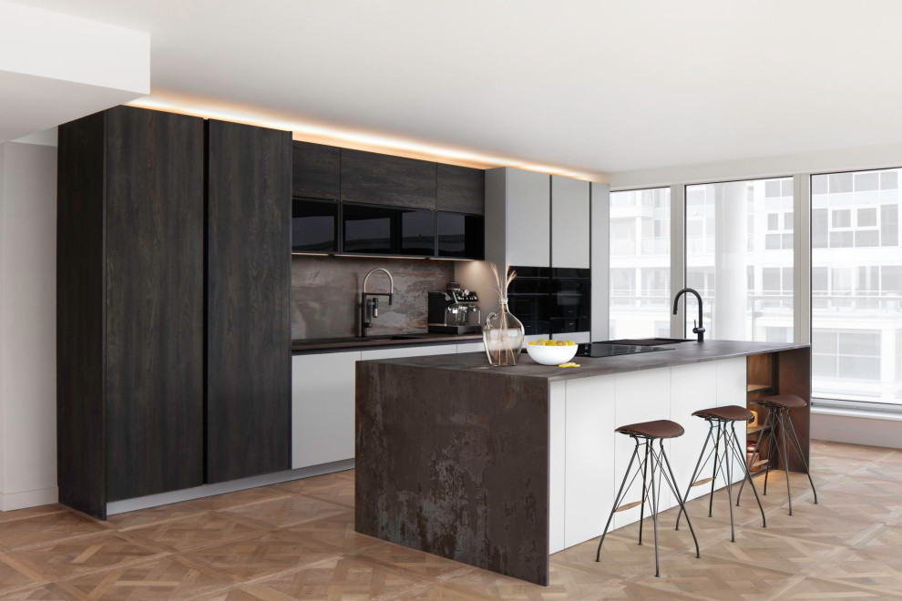 Photo of a large modern single-wall open plan kitchen in London with an integrated sink, flat-panel cabinets, dark wood cabinets, quartz benchtops, brown splashback, stone slab splashback, black appliances, medium hardwood floors, with island, brown floor and brown benchtop.