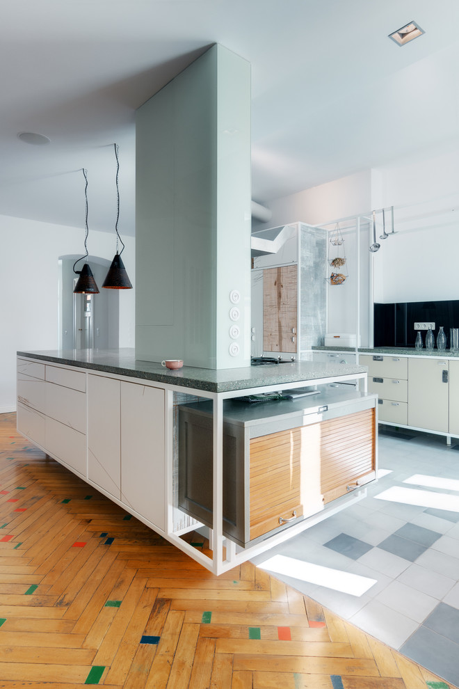 Inspiration for a large industrial galley open plan kitchen in Berlin with black splashback, with island, flat-panel cabinets, white cabinets and marble benchtops.