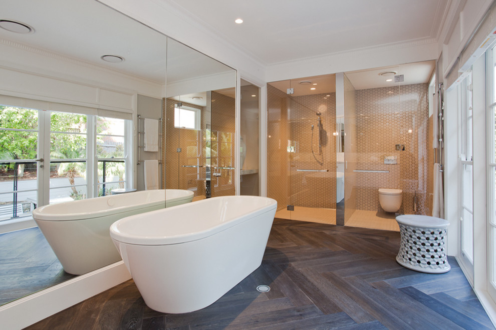 This is an example of a contemporary bathroom in Sydney with a freestanding tub, a curbless shower, a wall-mount toilet, brown tile and dark hardwood floors.