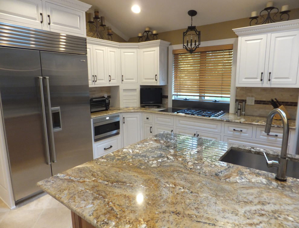 This is an example of a large traditional l-shaped eat-in kitchen in Minneapolis with an undermount sink, raised-panel cabinets, white cabinets, granite benchtops, beige splashback, stone tile splashback, stainless steel appliances, travertine floors and with island.