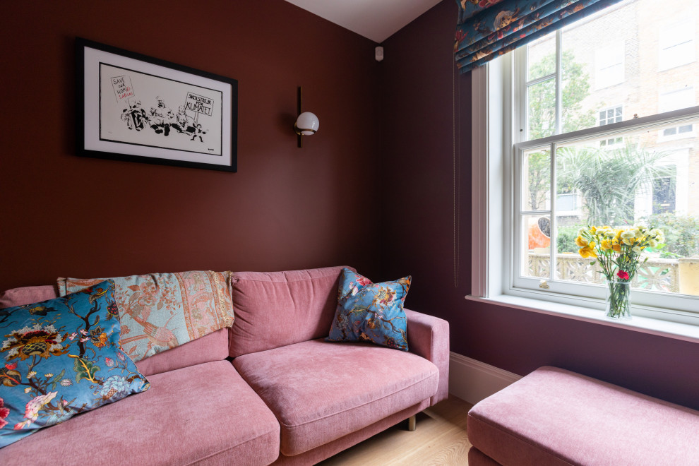 This is an example of a mid-sized living room in London with red walls, medium hardwood floors, no fireplace, a wall-mounted tv and brown floor.