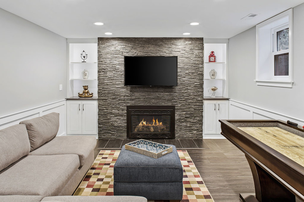 Photo of an expansive transitional look-out basement in Columbus with grey walls, vinyl floors, a standard fireplace, a stone fireplace surround and grey floor.