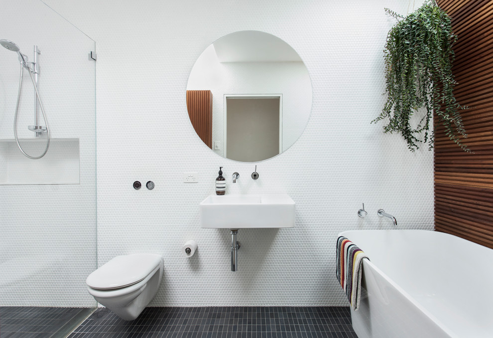 Contemporary master bathroom in Sydney with a freestanding tub, a curbless shower, white tile, white walls, a wall-mount sink, black floor, a single vanity and wood walls.