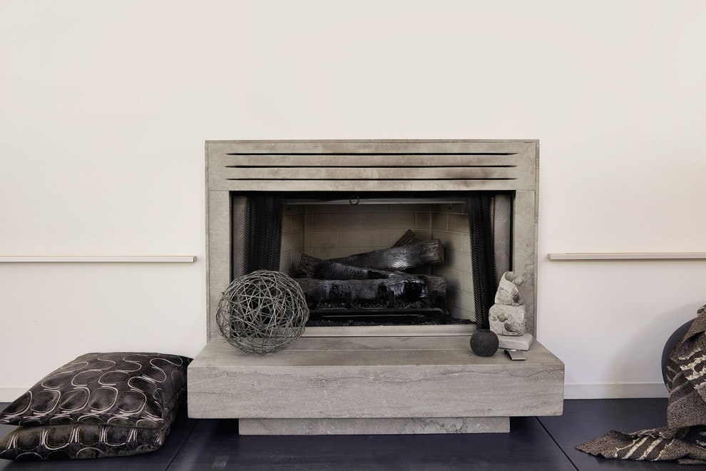 This is an example of a mid-sized modern open concept living room in Other with white walls, concrete floors, a standard fireplace, a concrete fireplace surround and black floor.