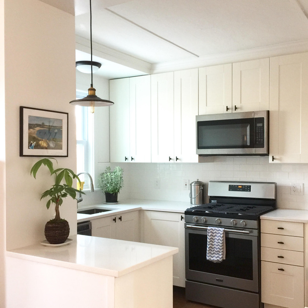 This is an example of a small country u-shaped eat-in kitchen in New York with an undermount sink, shaker cabinets, white cabinets, quartz benchtops, white splashback, ceramic splashback, stainless steel appliances, medium hardwood floors, a peninsula, white benchtop and coffered.