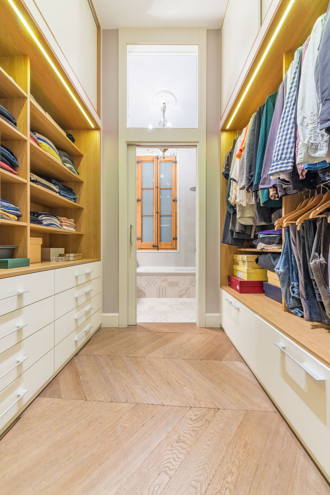 Imagen de vestidor unisex clásico renovado de tamaño medio con armarios abiertos, puertas de armario blancas, suelo de madera en tonos medios y suelo marrón