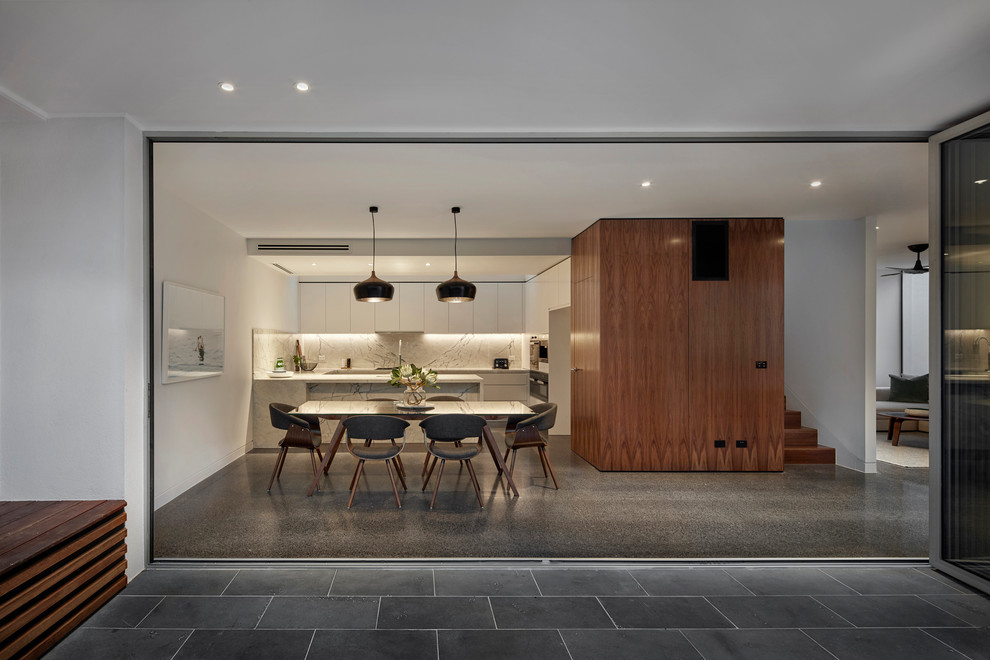 This is an example of a large contemporary kitchen/dining combo in Melbourne with white walls, concrete floors and no fireplace.