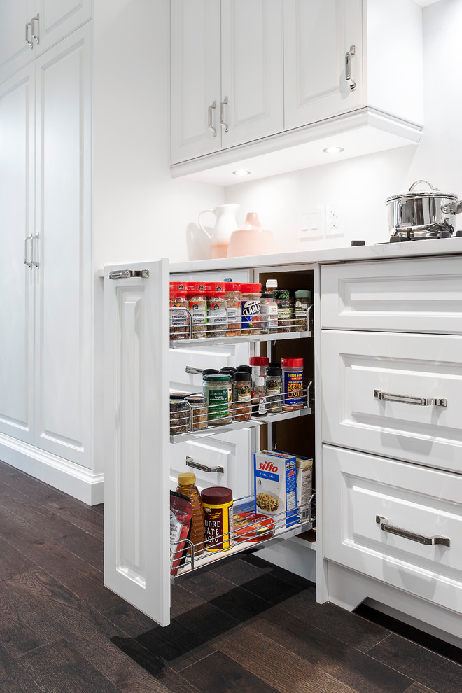 Mid-sized transitional l-shaped dark wood floor and brown floor kitchen photo in Toronto with an undermount sink, raised-panel cabinets, white cabinets, quartzite countertops, white backsplash, marble backsplash, stainless steel appliances, an island and white countertops