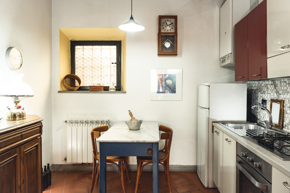 Exempel på ett litet modernt grå linjärt grått kök och matrum, med en nedsänkt diskho, släta luckor, vita skåp, laminatbänkskiva, grått stänkskydd, stänkskydd i mosaik, rostfria vitvaror, klinkergolv i terrakotta och rött golv