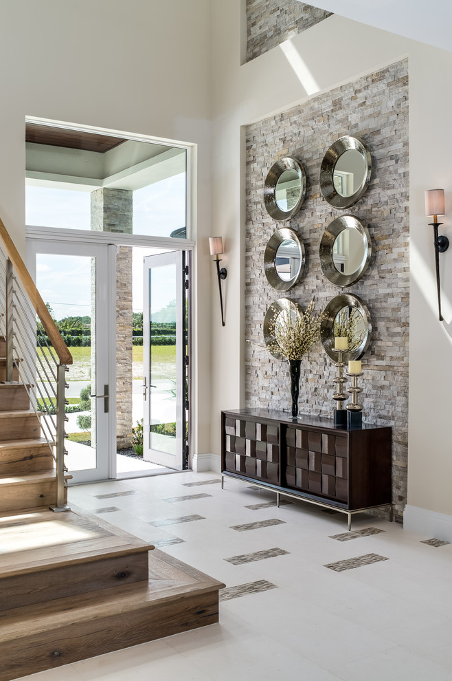 This is an example of a large transitional foyer in Miami with beige walls, a double front door, a glass front door, white floor and porcelain floors.