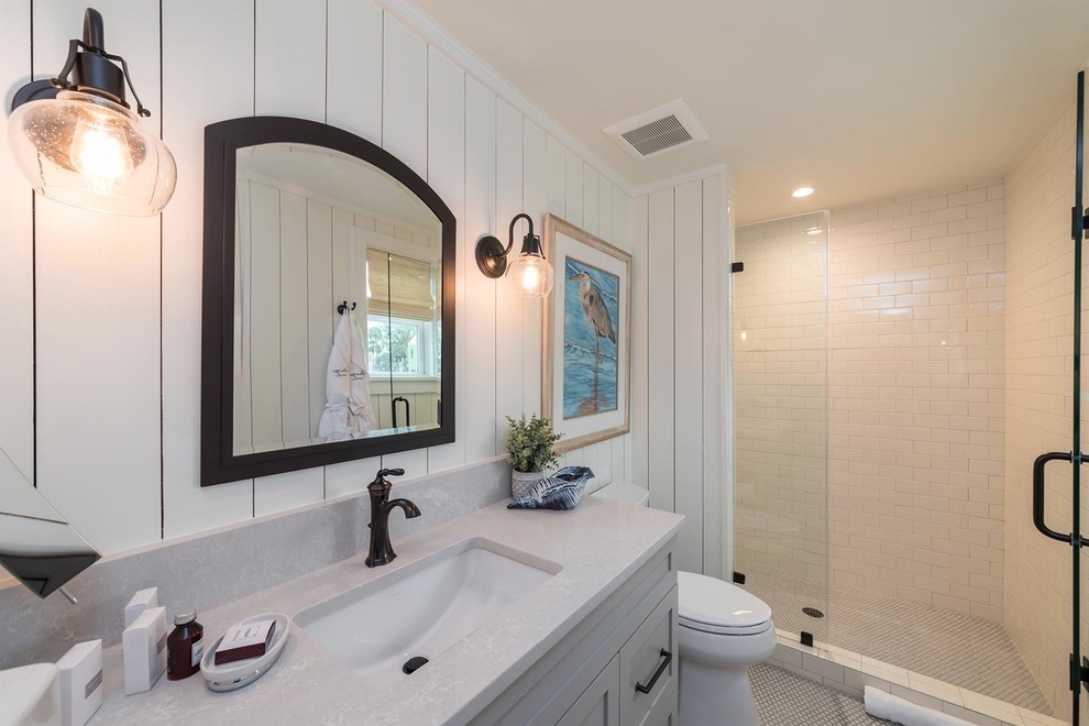 Large beach style 3/4 bathroom in Atlanta with shaker cabinets, grey cabinets, an alcove shower, a two-piece toilet, white tile, subway tile, white walls, mosaic tile floors, an undermount sink, quartzite benchtops, white floor, a hinged shower door and grey benchtops.