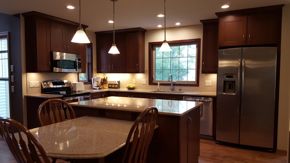 Example of a large transitional l-shaped vinyl floor eat-in kitchen design with an undermount sink, shaker cabinets, dark wood cabinets, quartz countertops, beige backsplash, subway tile backsplash, stainless steel appliances and an island