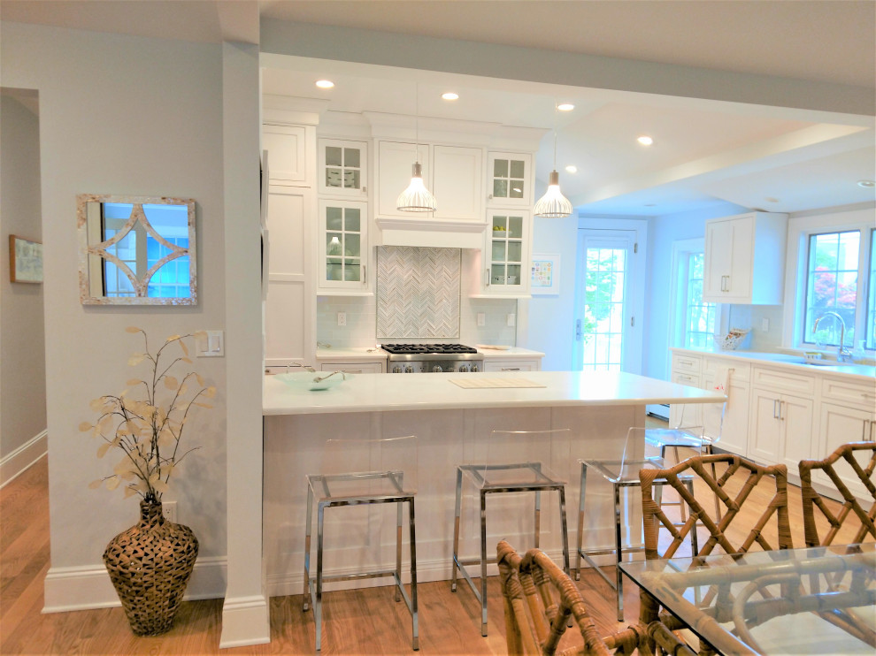 This is an example of a medium sized coastal u-shaped kitchen/diner in New York with shaker cabinets, white cabinets and a breakfast bar.