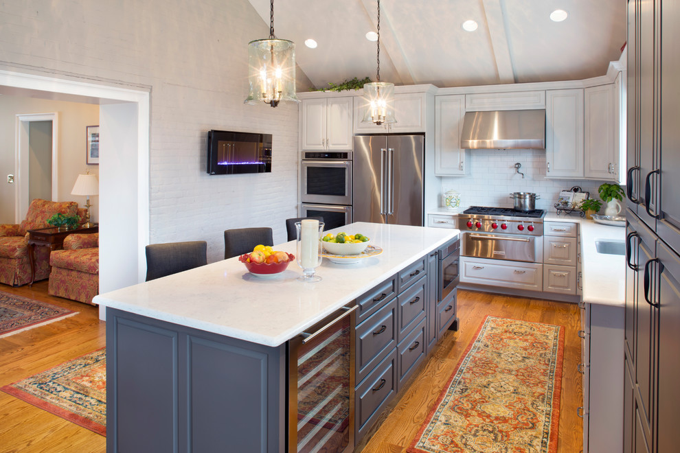Eat-in kitchen - mid-sized transitional medium tone wood floor and brown floor eat-in kitchen idea with an undermount sink, raised-panel cabinets, white cabinets, quartz countertops, white backsplash, ceramic backsplash, stainless steel appliances and white countertops