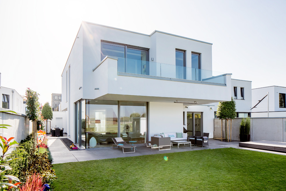 Design ideas for a large contemporary two-storey stucco white house exterior in Dusseldorf with a flat roof.